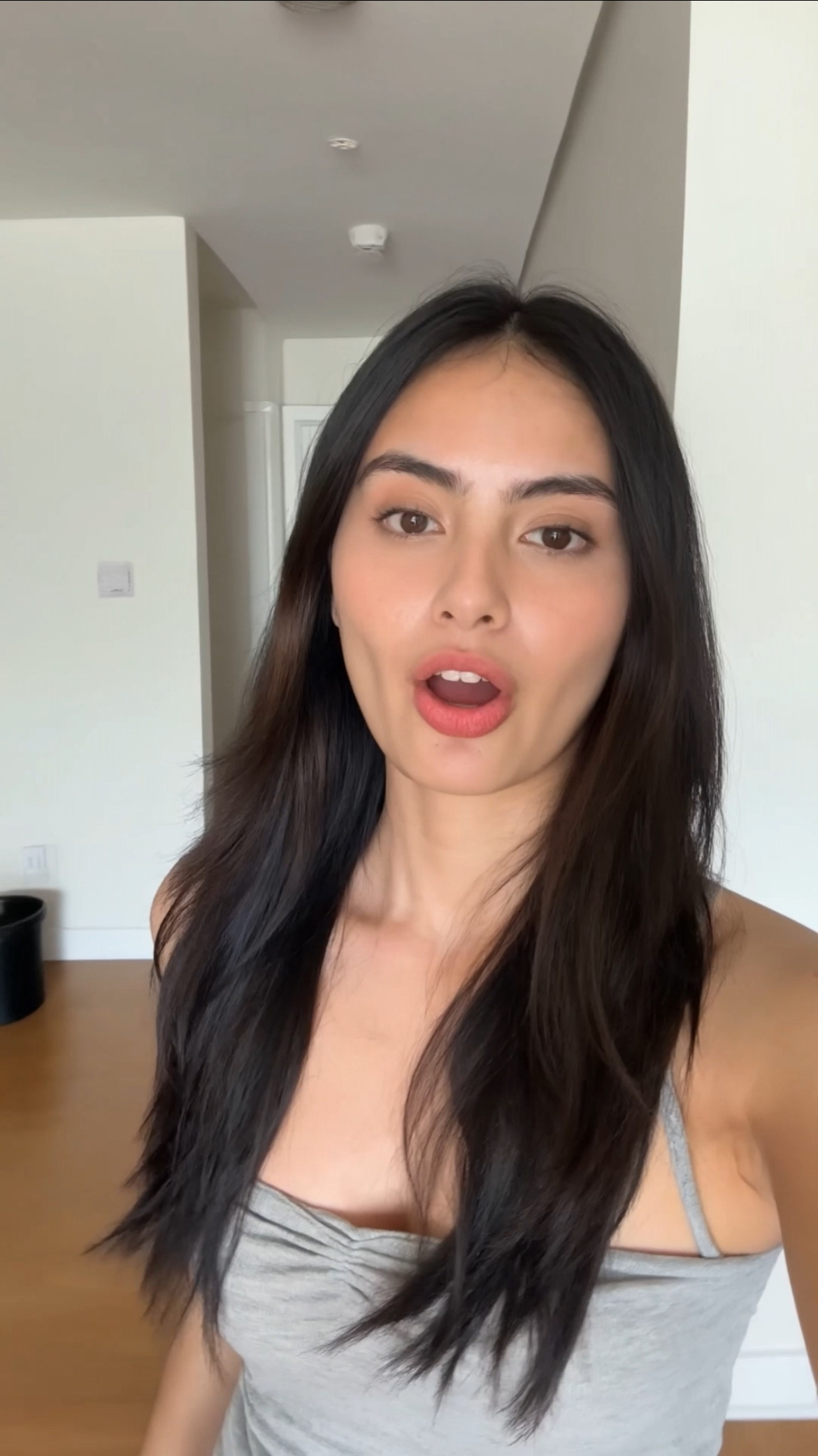 A close-up handheld selfie video tracking a young woman with natural makeup walking…